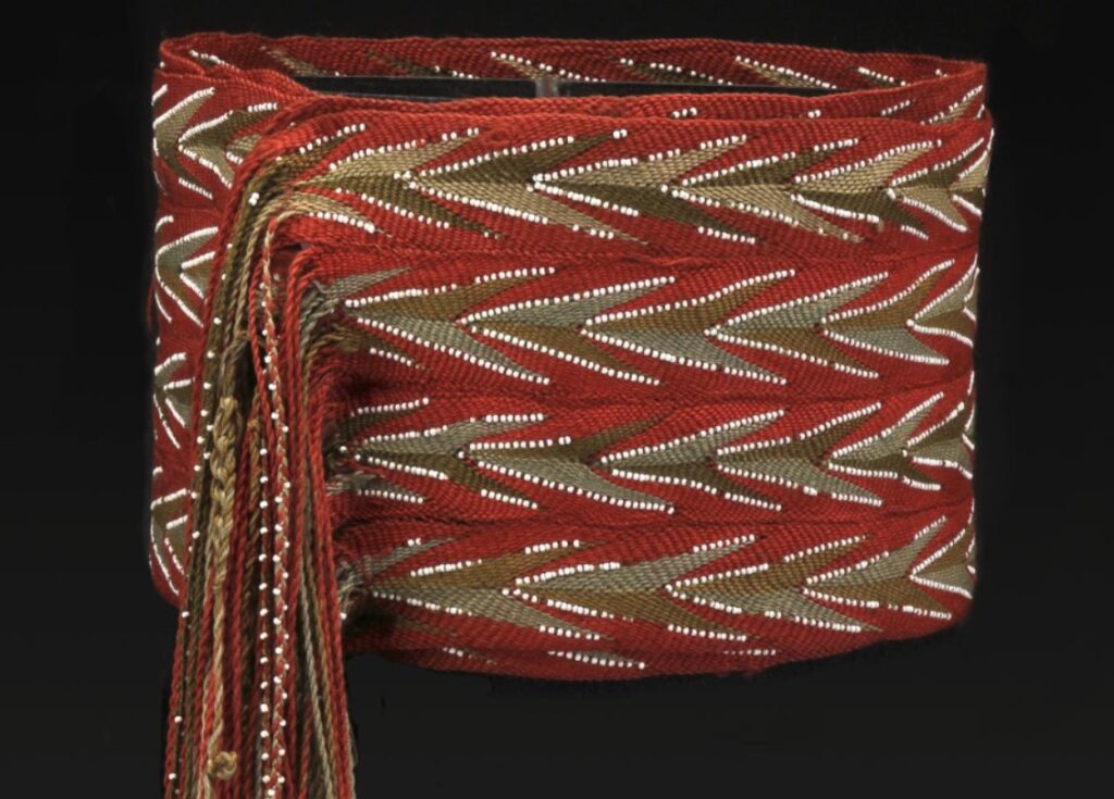 Detail plně vyvinutého huronského typu sashe ceinture perlée z let 1840-80. Tato 17cm široká a 302cm dlouhá (včetně třásní) sash se nosila dvakrát omotaná kolem pasu. Byla sešita ze čtyř pruhů, z nichž dva a dva jsou shodných barev. Jejich prostřídáním vzniká živý, nestereotypní efekt, což je známkou vysoké umělecké kultivovanosti tvůrce. Musée McCord.