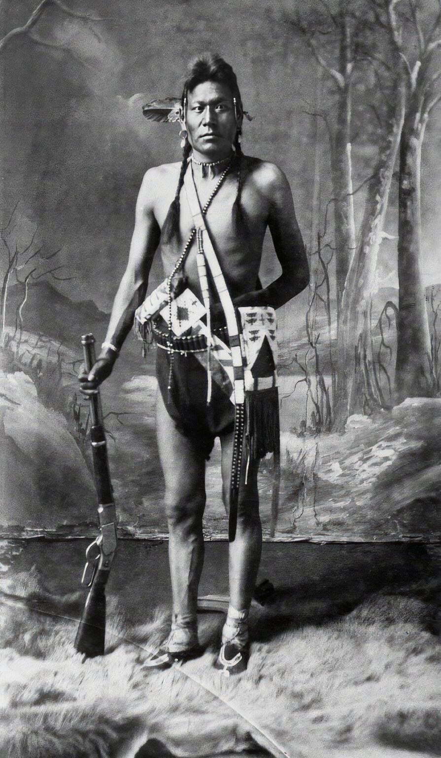 Bojovník kmene Černonožců s opakovací karabinou Winchester 1873 na dobové fotografii.