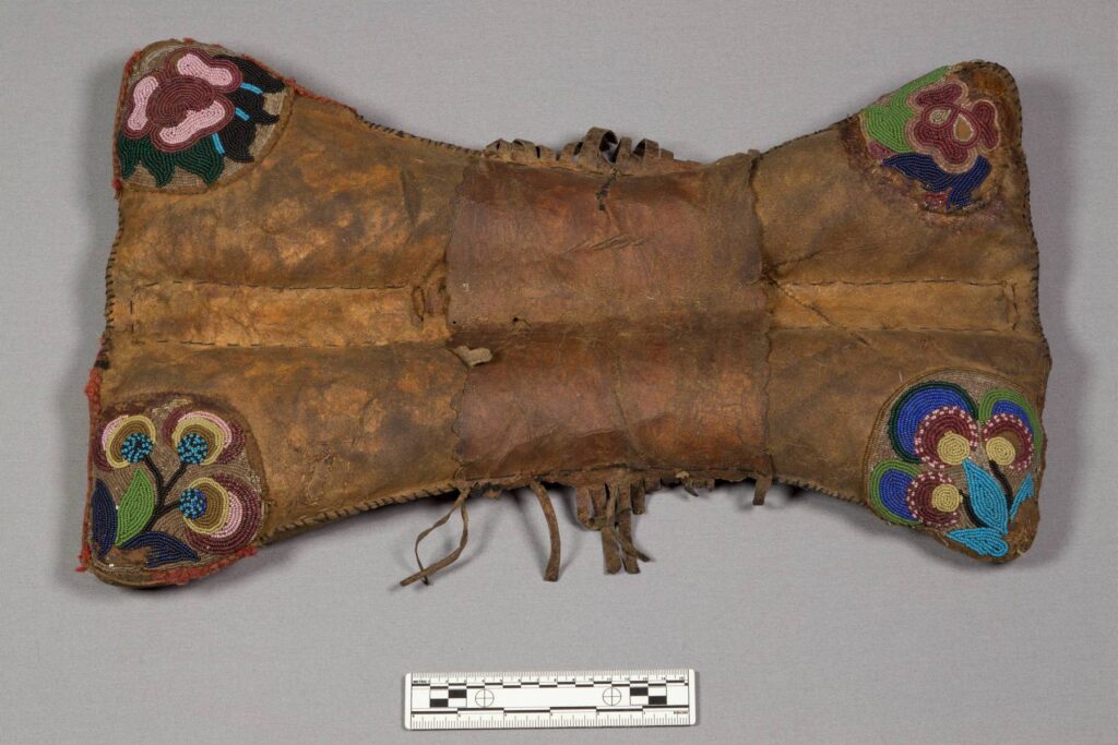 Polštářové sedlo kmene Kríů. Jeho rohy jsou zdobeny korálkovou výšivkou s květinovým motivem. Taková sedla vyráběli i Odžibwejové, ovšem ti většinou používali, na rozdíl od Kríů jako podklad korálky bílé barvy. Sbírka NMNH.