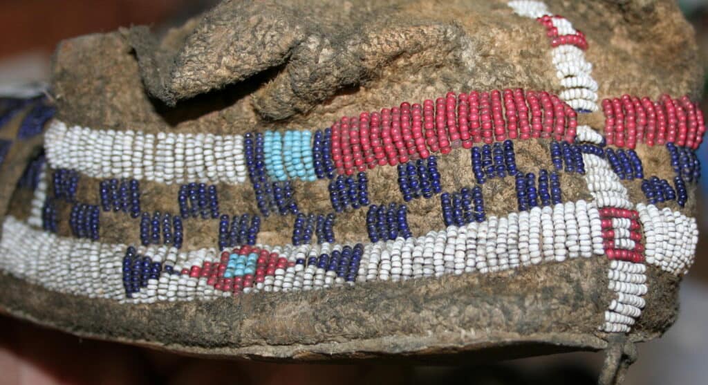 Detail originální šajenské mokasíny. Je vyrobena z bizoní vyčiněné kůže. Korálky jsou vyšité přímo do této kůže.
