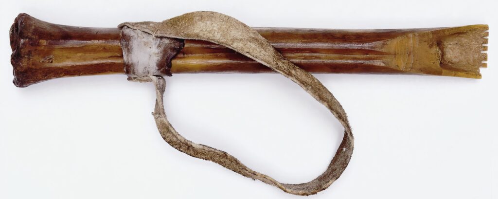 Škrabka flesher, v tomto případě vyrobená z kosti. Existovaly ale i exempláře železné. Některé se vyráběly i z hlavní pušek. Každý flesher měl zuby, kterými trhal zbytky masa, blan a tkání.