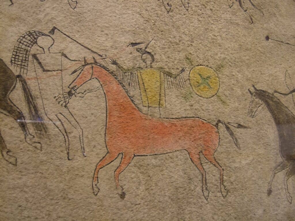 Piktogram z lakotského pláště z 1.poloviny 19.století zobrazuje koně s uzdou ozdobenou řetízky nebo navažskými coscojos.