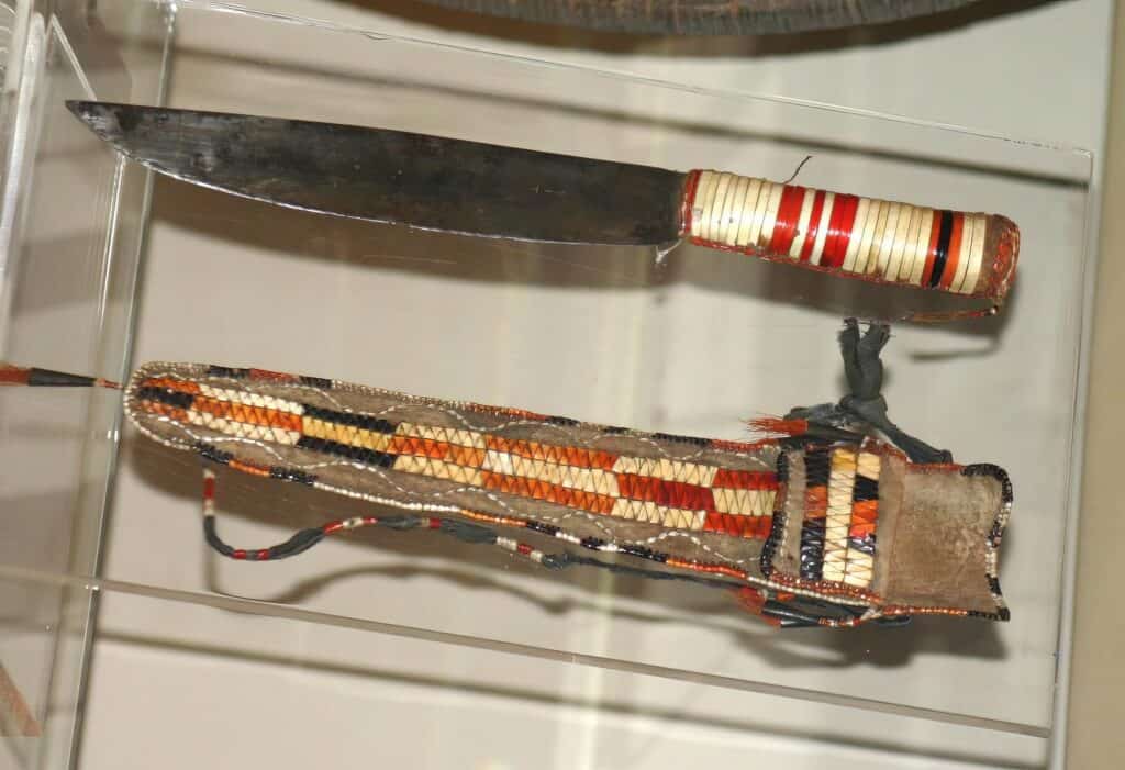 Typický "scalper", pravděpodobně francouzského původu. Indián si upravil a dozdobil ručku ursoními ostny, aby více odpovídala jeho představám. K noži je i pouzdro, které se nosilo kolem krku. British museum, Londýn.