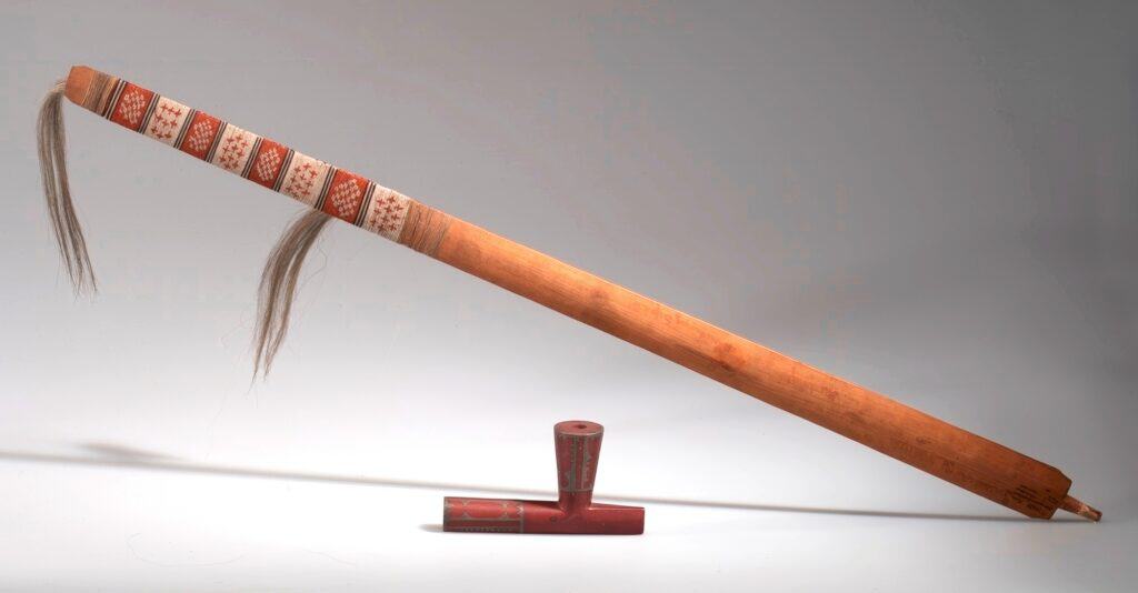Luxusní dakotská dýmka s catlinitovou hlavičkou vylévanou cínem a širokou jasanovou troubelí omotanou jemným řetízkem z ursoního quillu je klasickou ukázkou vrcholné práce éry kolem roku 1850, kdy řemeslné zpracování dýmek dosahovalo nejvyšší úrovně (AMNH).