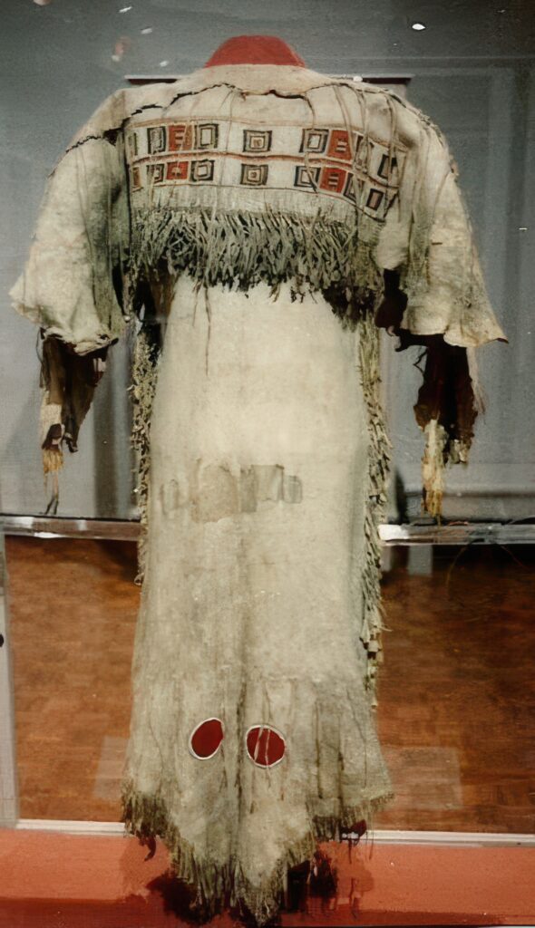 Kríjský typ šatů ze dvou kůží, angl. tail dress. (Sbírka Paula Kanea, Manitoba Museum of Man and Nature). Typ šatů vpravo, převzatý patrně od Černonožců, nezapře svým zdobením starší tradici přehnutých šatů. Oboje šaty mají třásně zdobené omotávkami z ursoních ostnů.